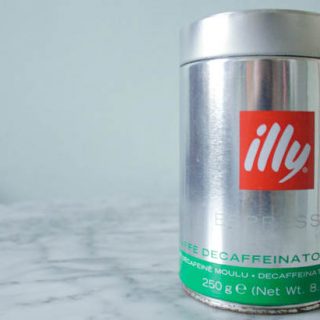 An Illy Decaf coffee tin sitting on a marble table top