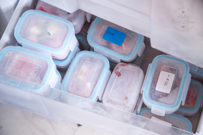 Freezer drawer filled with tightly stacked plastic tubs